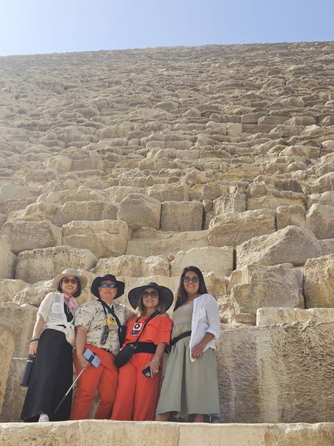 A group of people posing in front of an ancient Egyptian pyramid.