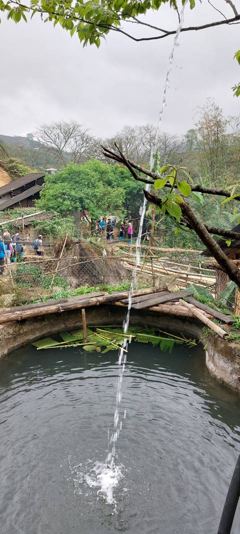 People crossing a rustic bridge over a small waterway.