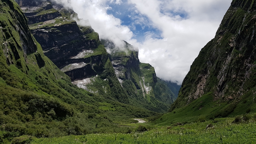 Majestic valley with towering cliffs and a river below.