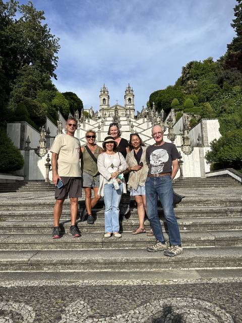 Group of people posing on steps with a historic structure in the background.