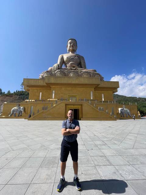 Person standing in front of a large Buddha statue.