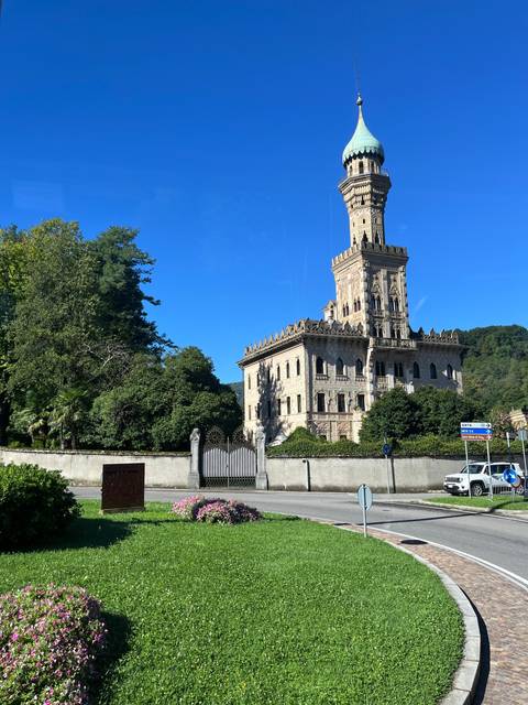 Historic building with a tall spire and well-maintained garden.