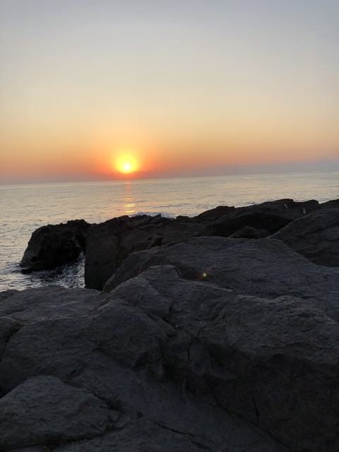       Ocean sunset view with rocky shoreline.
  