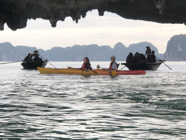 People kayaking on a calm sea with karst formations.