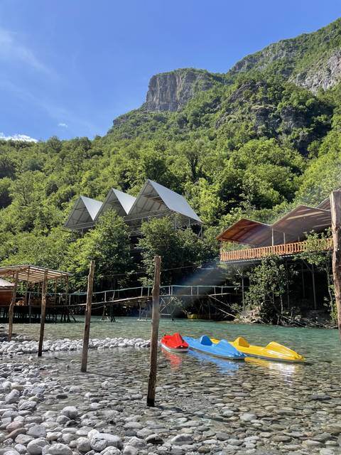 Kayaks on the riverbank near a pavilion.