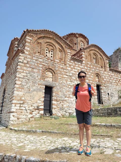       Woman posing in front of an old church with stone architecture.
  