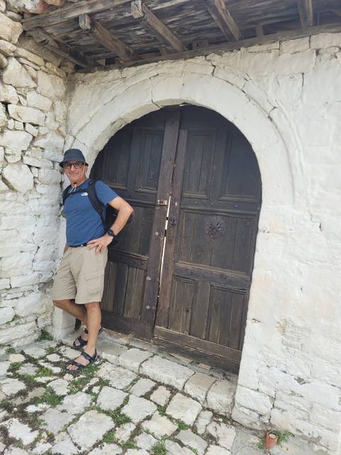       Man posing in a door with an arch-shaped entrance.
  