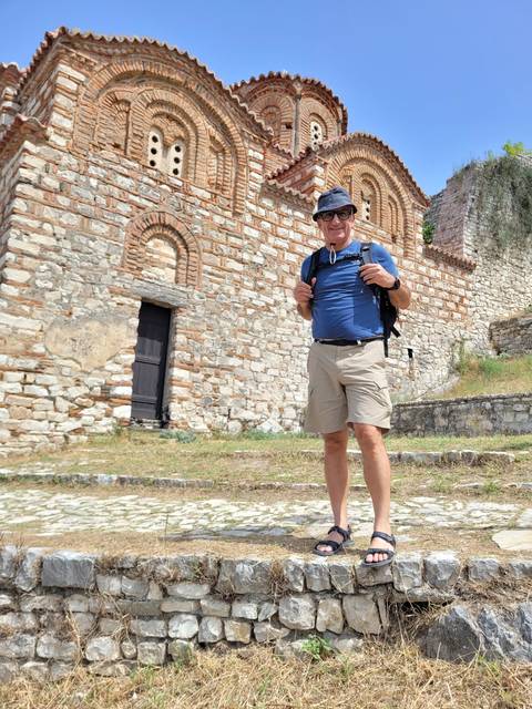 Man posing in front of a historic stone church.