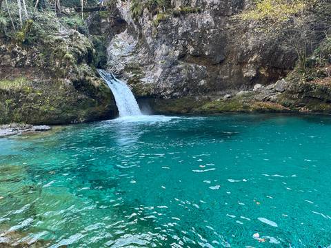       Small waterfall flowing into emerald green water.
  