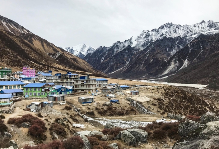       Colorful mountain village under towering peaks.
  