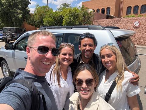 Group photo of people in front of a vehicle.