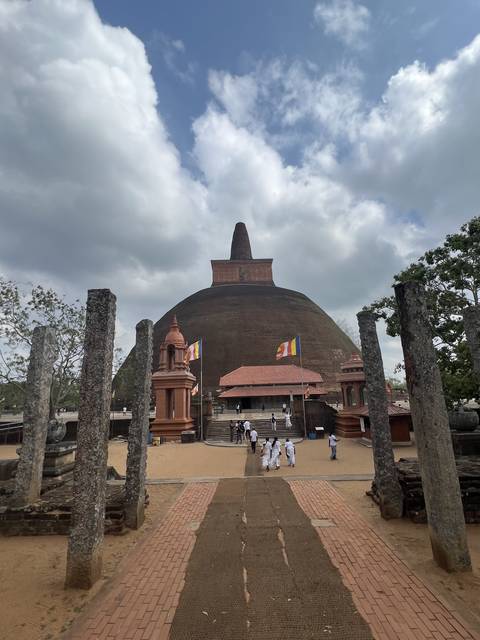 Large red stupa with people walking around.