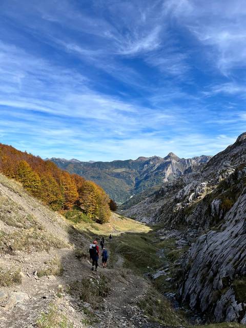       Hikers on a mountain trail with panoramic views.
  