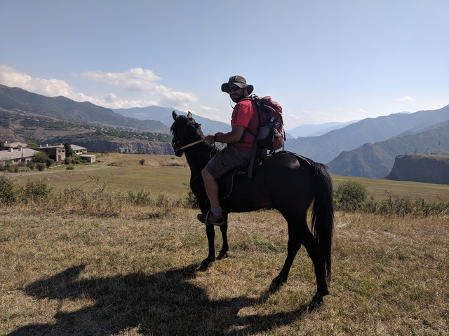       Man on a horse with a scenic mountain backdrop.
  