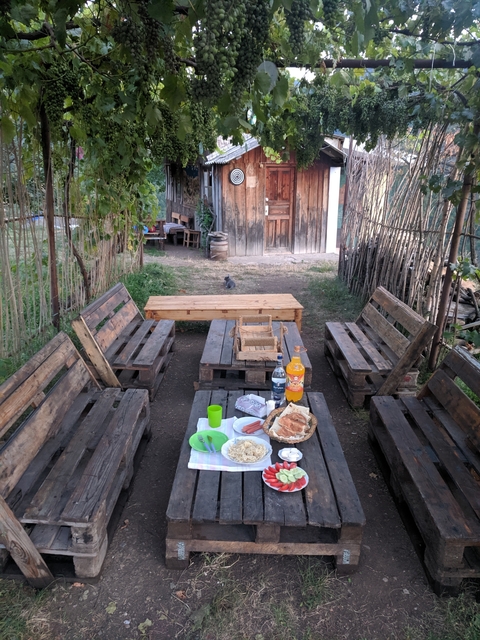       Simple outdoor seating setup with wooden furniture and drinks on a table.
  