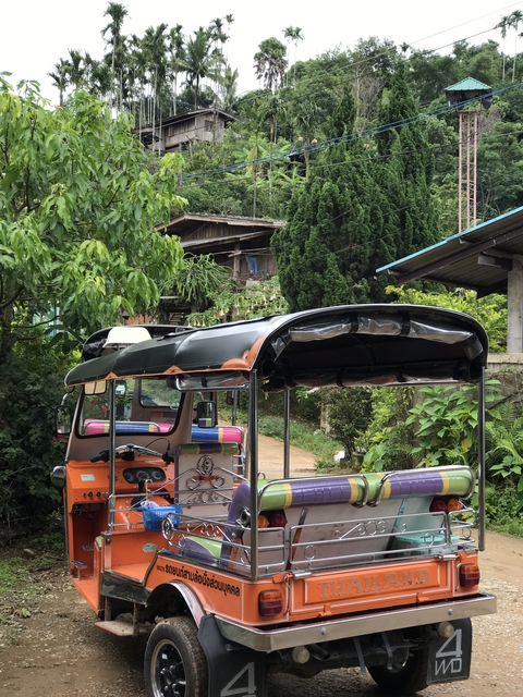 Orange tuk-tuk in a village setting.