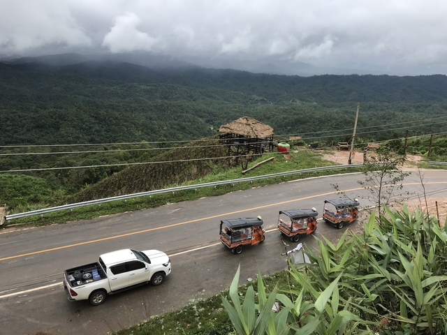 Panoramic view of mountains and highway with tuk-tuks.