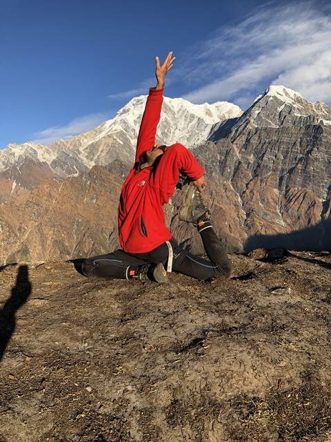 Person doing a yoga pose with mountains in the background.