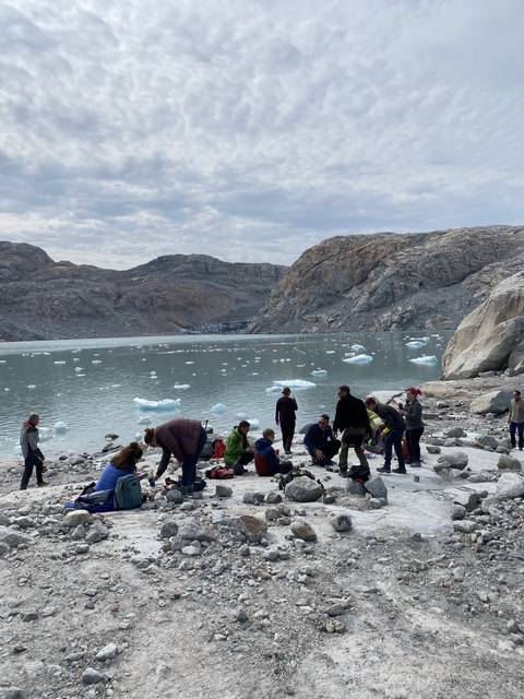 Group of people by the water with icebergs.