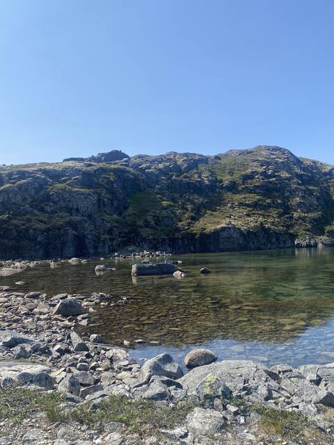       Clear water surrounded by rocky hills.
  