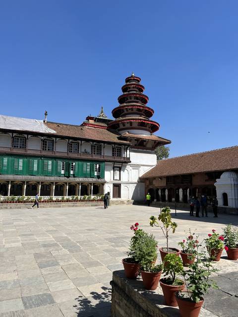       A traditional pagoda temple next to a courtyard with potted plants.
  