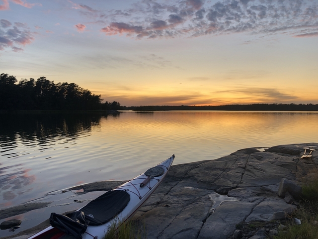 Kayak on the shore at sunset with calm water