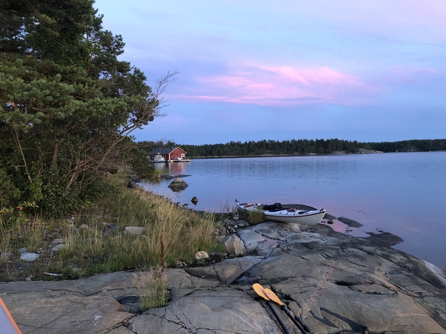 Kayak on a rocky shore with a calm lake and pink sky