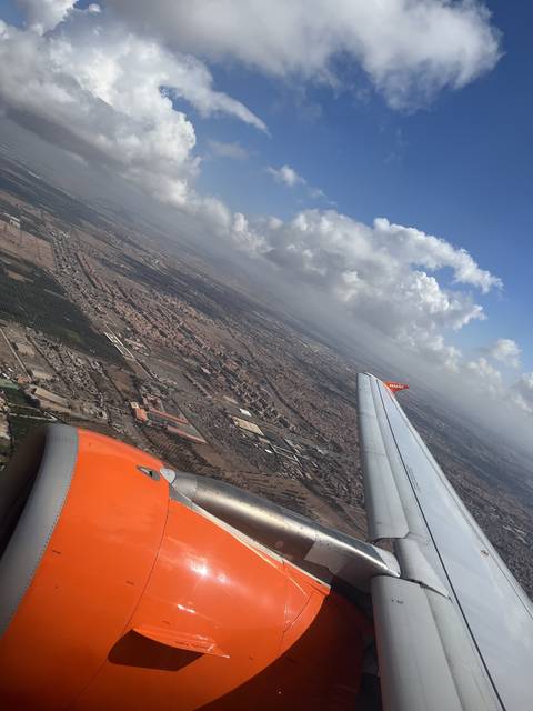       View from airplane window showing a landscape with clouds and aircraft wing.
  