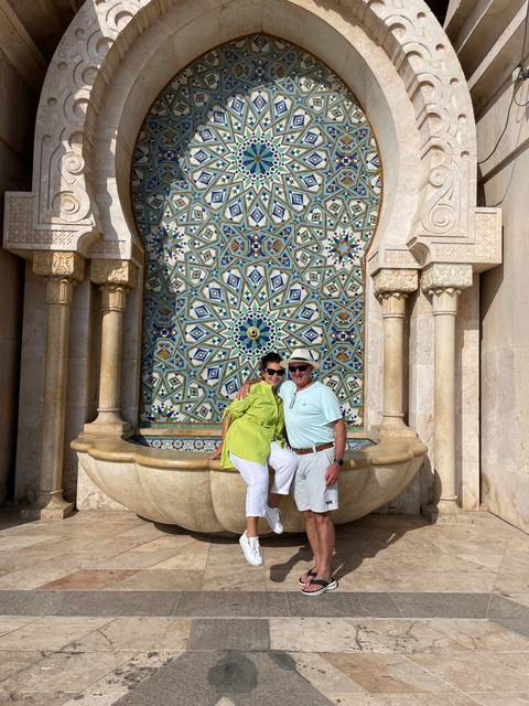       Couple posing beside a decorative tiled fountain.
  