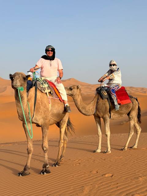 People riding camels in the desert.