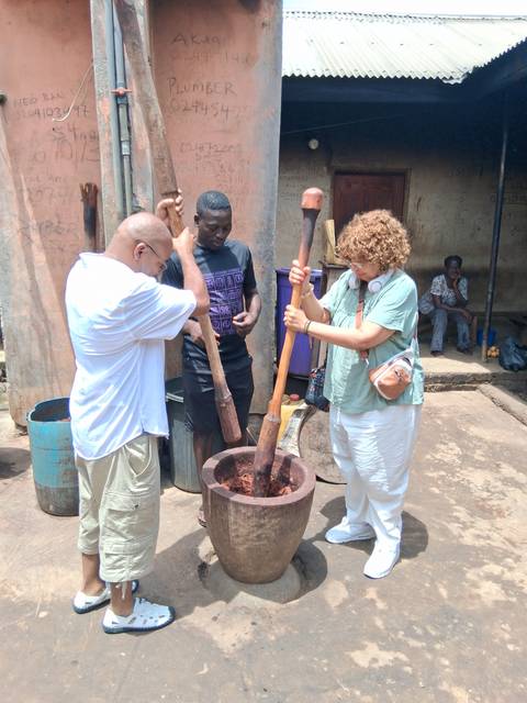 People pounding something in a traditional wooden mortar.
