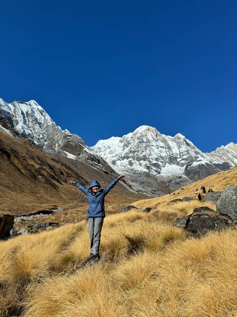 Person with arms raised in front of snowy mountains.