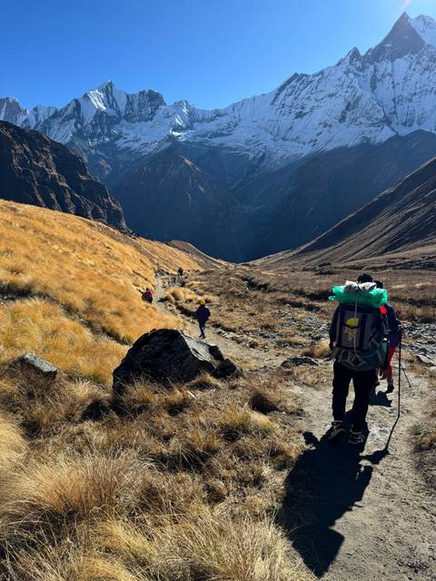 Hikers on a trail with mountains in the background.