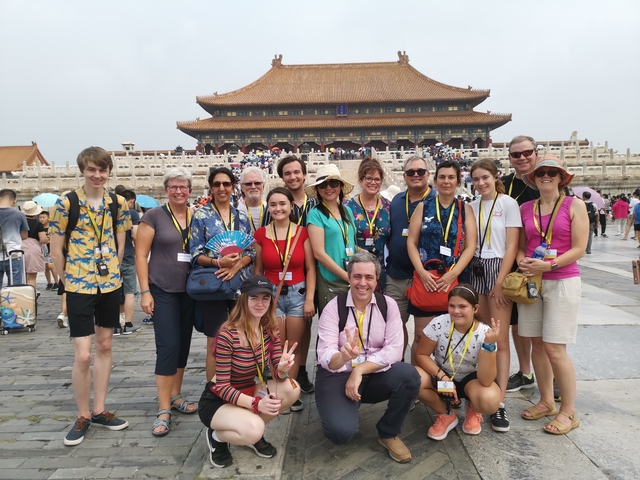 Group photo at the Forbidden City with a large crowd in the background.