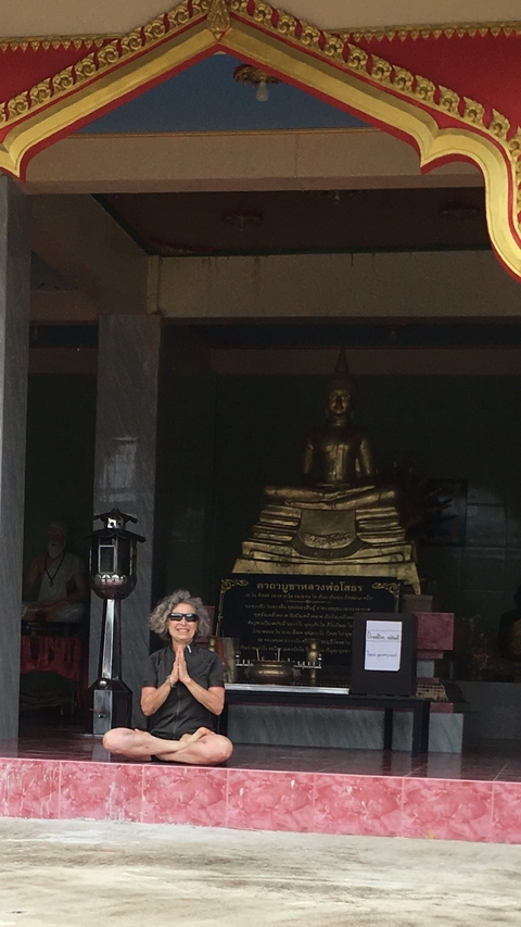Dimly lit statue of a seated Buddha inside a building.
