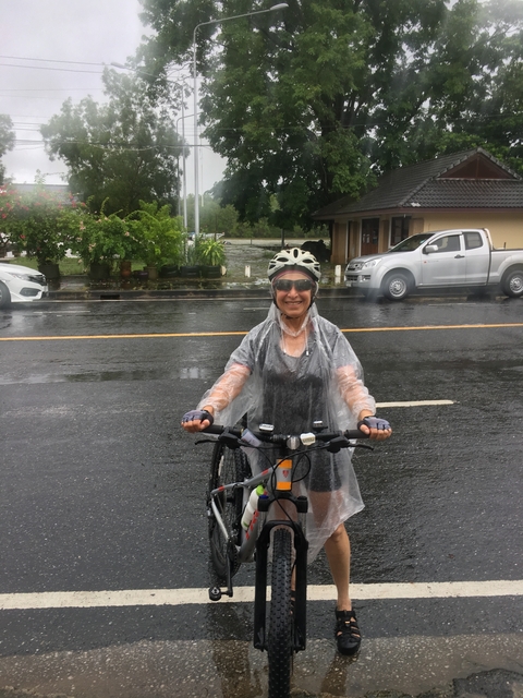 Cyclist in rain gear smiling on a wet road.