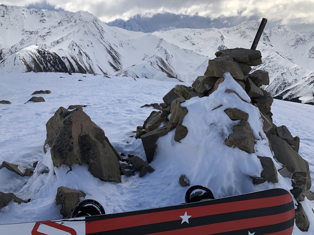 Snow-covered rocky terrain with distant mountain view.