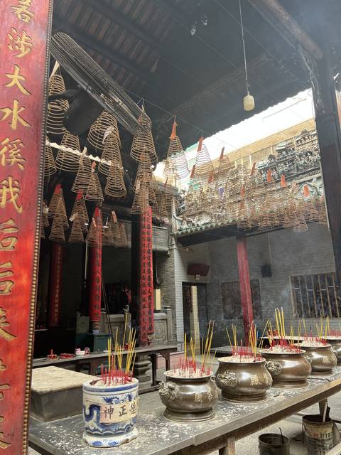Inside a temple with incense coils hanging from the ceiling.