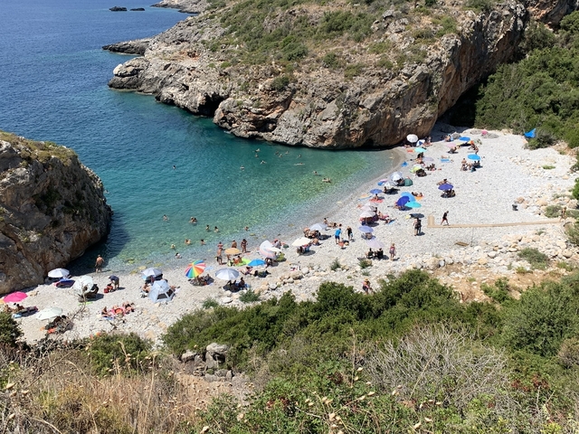 Pebble beach with umbrellas and swimmers