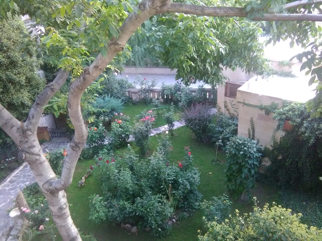Lush garden with blooming flowers and trees surrounding a pathway.