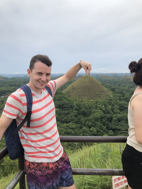       Person pointing at the Chocolate Hills in Bohol.
  