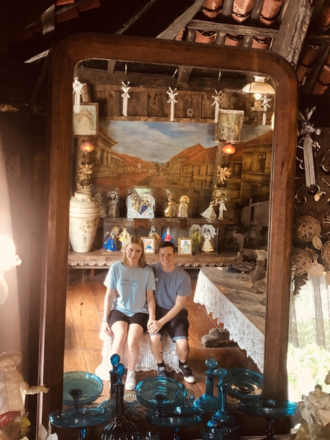       Two people seated in a room with religious artifacts.
  
