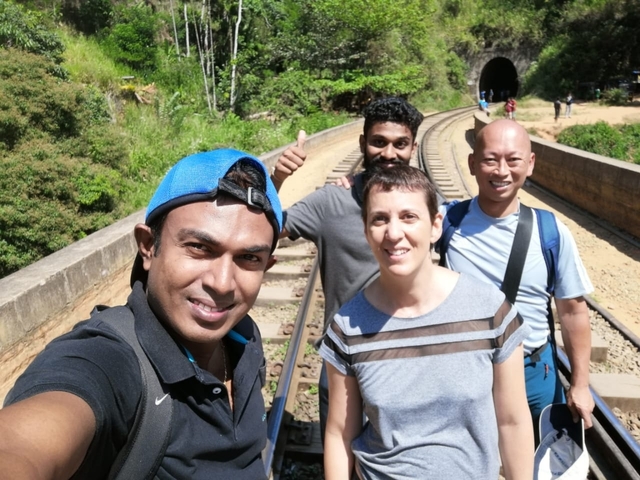       Group of people on railway tracks giving thumbs up.
  
