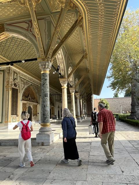 People walking in an ornate courtyard with decorated columns.