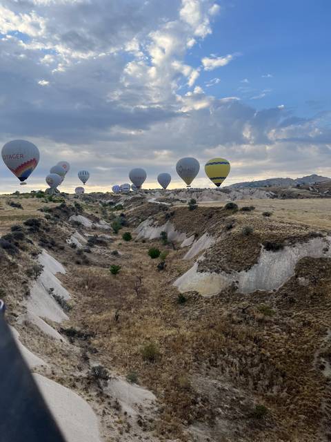 Hot air balloons flying over a rocky landscape with blue skies.