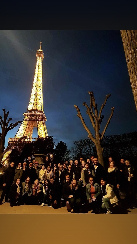 Night view of people near the illuminated Eiffel Tower.