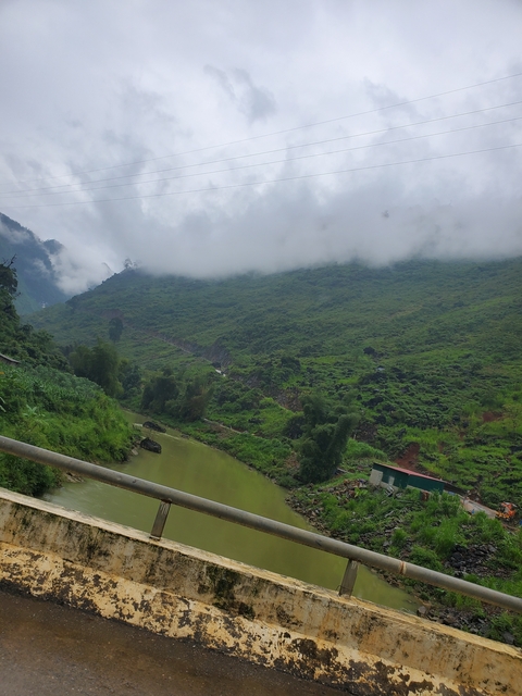       Foggy view of a lush green valley with a river.
  
