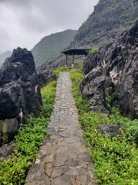       Stone path through rugged mountains with greenery.
  