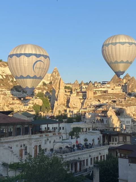       Hot air balloons above a rocky landscape and buildings
  