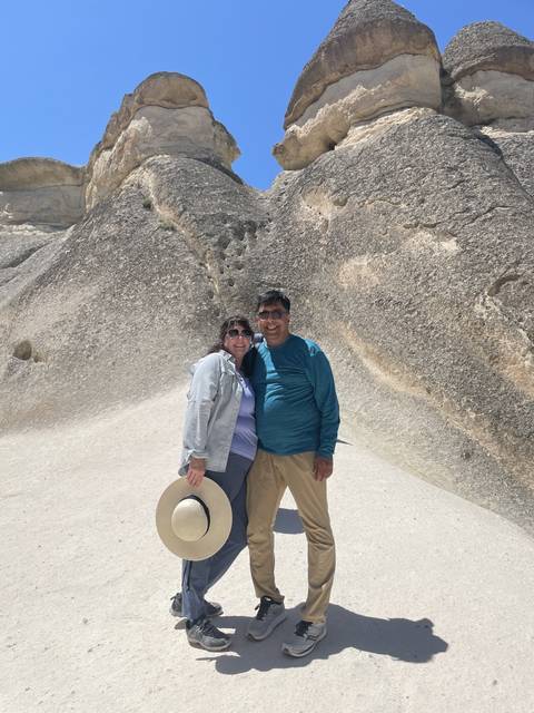       Two people posing in front of large rock formations.
  